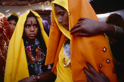 Bár illegális, mégis gyakori a gyermekházasság Indiában. A szemmel láthatóan még gyereklány kezében a saját gyermekét tartja.  Aki nem az elsőszülött, ugyanis a háta mögött ülő kisfiú is az övé.