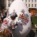 Kalocsai népviseletben kalocsai mintával festi ki az óriás tojást egy hímzőasszony. 