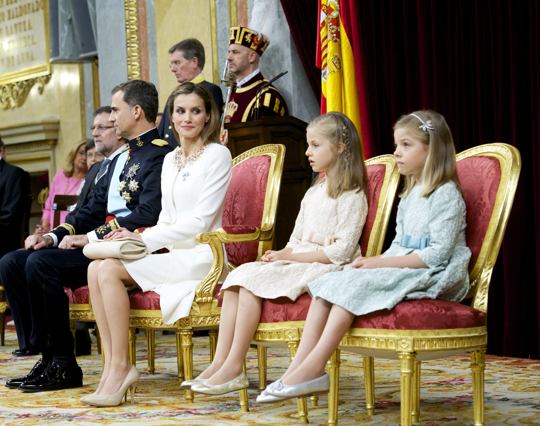 Letícia visszafogott kabátjának nyakánál a díszítés a spanyol zászló színeiben csillog, a két lány, Zsófia és Eleonóra ruhája pedig tökéletesen illik anyjuk szettjéhez.